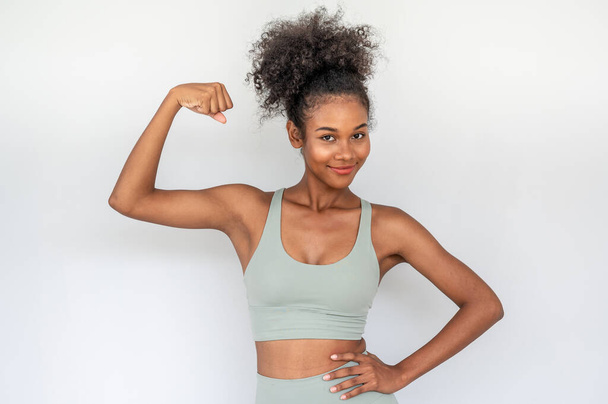 Happy beautiful young african woman wearing sportswear  showing arms muscles smiling with confident and proud on white background. fitness concept. - Foto, imagen