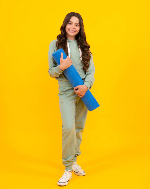 Teenage girl dressed in sports uniform, posing in the studio. Child in a posh stylish sports suit in a hoodie with a hood. Advertising sportswear and yoga wear. Healthy kids lifestyle, sport - 写真・画像