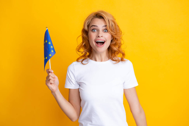Young excited woman holding flag of europe union, isolated on yellow. EU association. Happy girl holding flag of European Union, immigration and travelling in Europe - Foto, Bild