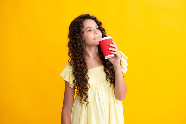 Teenage girl with take away cup of cappuccino coffee or tea. Child with takeaway cup on yellow background, morning drink beverage. Happy teenager portrait. Smiling girl - Foto, Imagem
