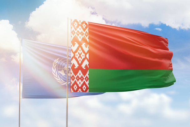 Sunny blue sky and flags of belarus and united nations - Foto, afbeelding