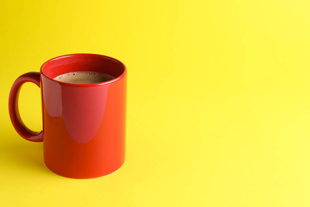 Red mug of freshly brewed hot coffee on yellow background, space for text - Photo, Image