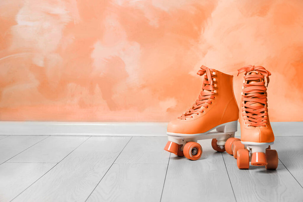 Vintage roller skates on floor near orange wall. Space for text - Foto, Bild