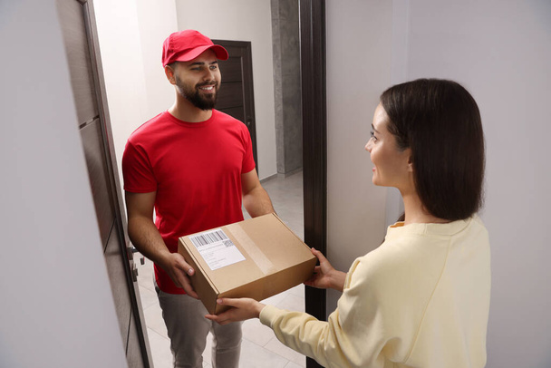 Woman receiving parcel from courier at home - Foto, afbeelding