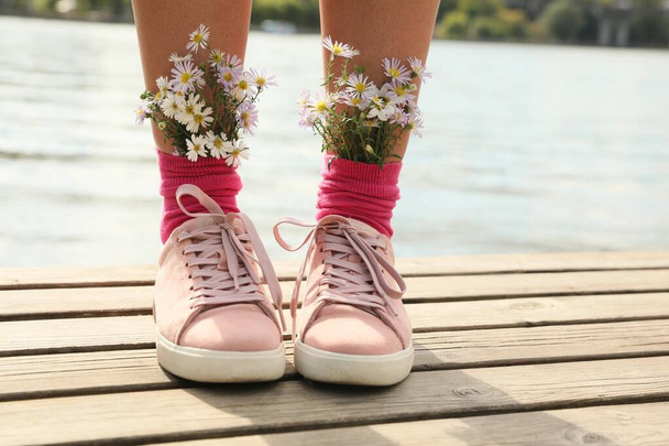 Woman with beautiful tender flowers in socks on wooden pier, closeup - Φωτογραφία, εικόνα