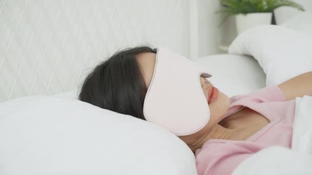 Beautiful young asian woman wearing cover eye and sleeping on bed with head on pillow comfort and happiness in the bedroom at home, girl with relax and leisure for wellness, lifestyles concept. - Footage, Video