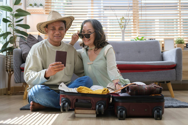Ευτυχισμένο ζευγάρι ετοιμάζεται για το ταξίδι, συσκευασίας βαλίτσες για το ταξίδι. Δραστηριότητα μετά τη συνταξιοδότηση, έννοια οικογενειακές διακοπές. - Φωτογραφία, εικόνα