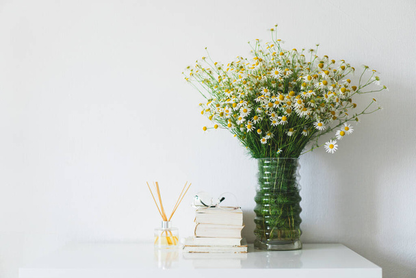 Incense sticks for the home with a floral scent. Book, Incense sticks and vase with chamomile flowers. The concept of eco-friendly fragrance for the home. Spa therapy, aromatherapy. - Φωτογραφία, εικόνα