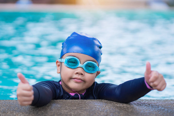 little girl smiling wearing swimming glasses in swimming pool. children playing in swimming pool on summer - Foto, imagen