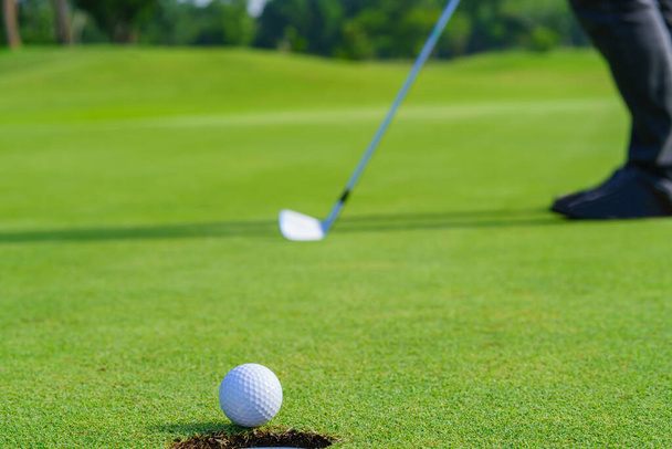 Golfçü golf sahasında topu yeşildeki deliğe attı.. - Fotoğraf, Görsel