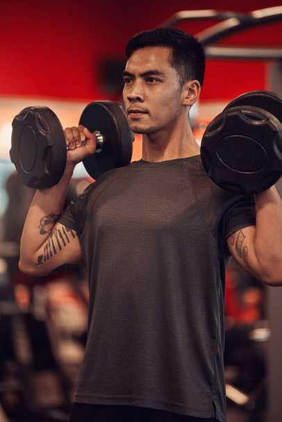 No excuses get that workout in. a young man lifting weights at the gym - Zdjęcie, obraz