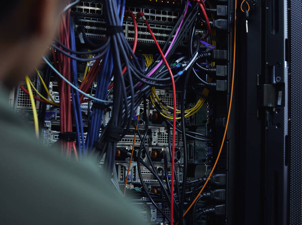Lets organize this cabling. an unrecognizable male IT support agent working in a dark network server room - 写真・画像