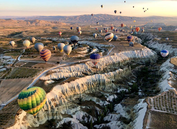 A bird's eye view of colorful hot air balloons above a beautiful valley in Cappadocia, Turkey - 写真・画像