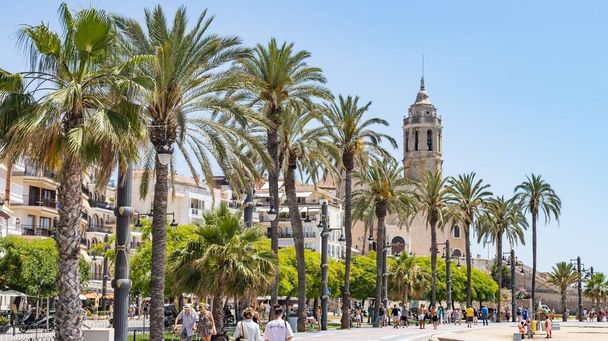 Sitges, Spain - June 12, 2022: Sitges seafront promenade with the background of the church of Sant Bartomeu and Santa Tecla in Sitges (Spain). - Фото, зображення