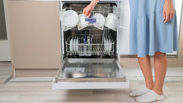 Žena v domácnosti bere čisté talíře z myčky nádobí - Fotografie, Obrázek