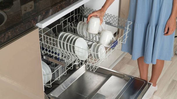 The housewife pulls out clean dishes from the dishwasher. High quality photo - Foto, Bild