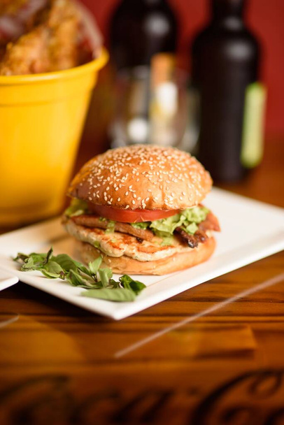 Uno scatto verticale di un hamburger servito su un piatto bianco in un ristorante elegante - Foto, immagini