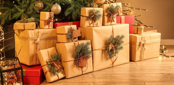 Many gift boxes under Christmas tree in living room in evening - 写真・画像