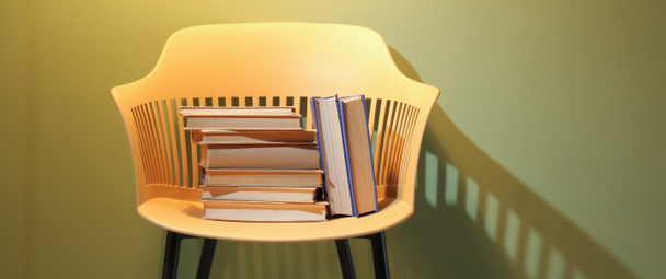 Chair with books near color wall - Фото, зображення