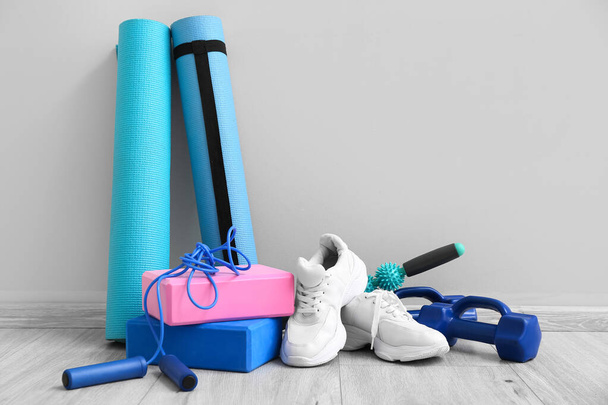 Sports equipment and sneakers on floor near light wall - Foto, afbeelding