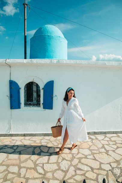beautiful woman in white dress near old greece church white with blue - Фото, изображение