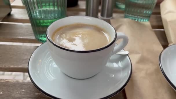Mok van verse koffie of latte met glas water op een tafel in cafe outdoor in de stad. Hoge kwaliteit 4k beeldmateriaal - Video
