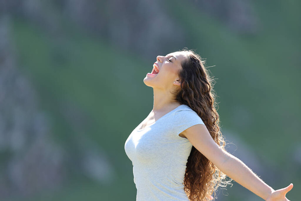 Profile of an excited woman screaming in the mountain - 写真・画像