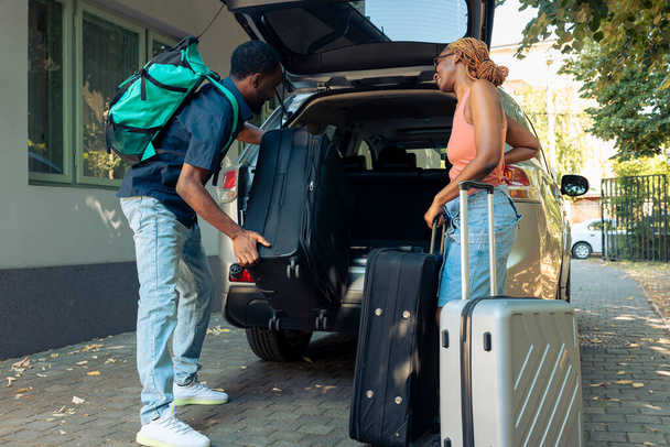 Boyfriend and girlfriend travelling on holiday, putting travel bags in trunk of automobile. Leaving on vacation trip for recreation. Couple in relationship going on urban adevnture with luggage. - Photo, image