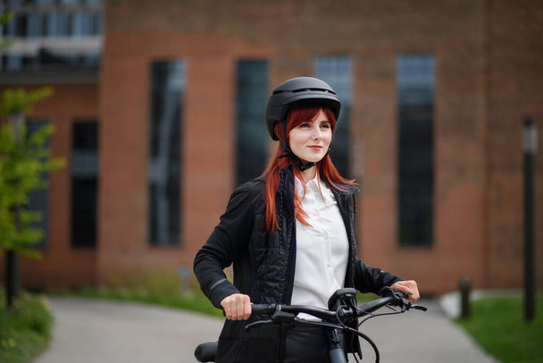 A portrait of businesswoman commuter on the way to work with bike, sustainable lifestyle concept. - Foto, Imagen