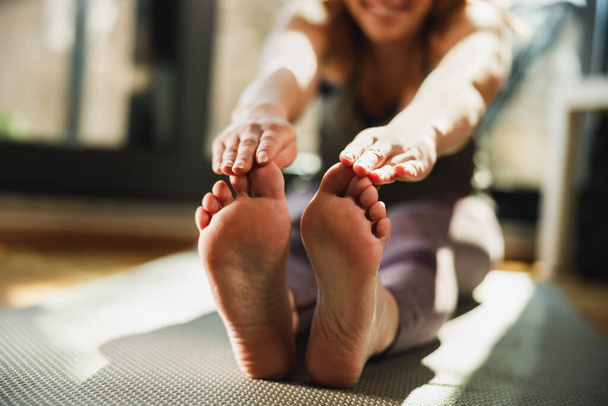 Cropped shot of a relaxed young woman doing stretching yoga exercises at home in the morning. - 写真・画像