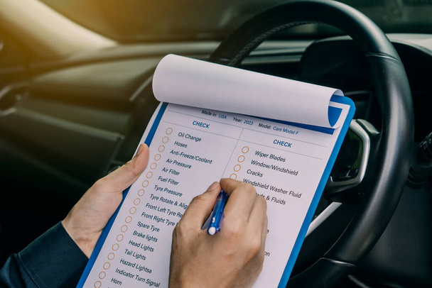 Machinic man in customer car writing to the clipboard the checklist for repair machine, car service and maintenance.Services car engine machine concept. - 写真・画像