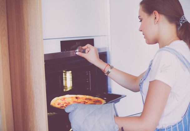 Happy young woman cooking pizza at home. - Fotografie, Obrázek