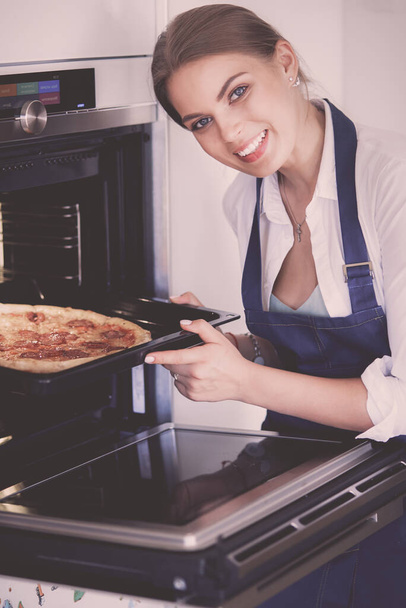 Happy young woman cooking pizza at home. - 写真・画像