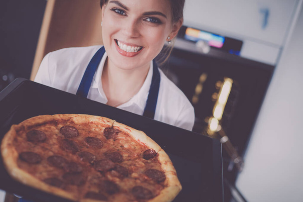 Happy young woman cooking pizza at home. - Valokuva, kuva