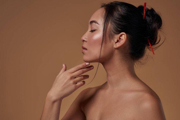 Profile of fashionable asian girl with closed eyes. Partial view of pretty young brunette slim woman. Female beauty. Isolated on orange background. Studio shoot. Copy space - Foto, immagini