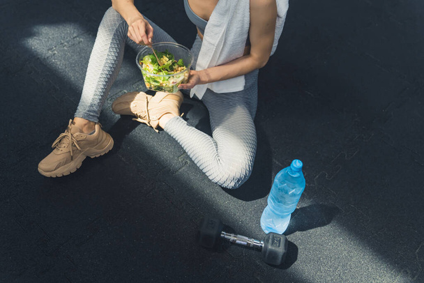 Вид зверху на жінку, яка відпочиває після вправ під час їжі здорового салату. . . Високоякісна фотографія
 - Фото, зображення