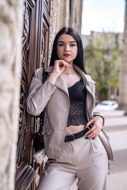 Fashionable young woman wear white leather jacket against old vintage house of city. - Foto, Bild