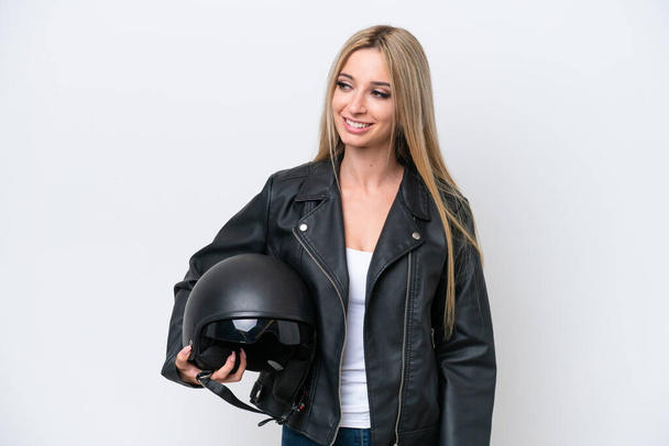 Pretty blonde woman with a motorcycle helmet isolated on white background looking to the side and smiling - Foto, afbeelding