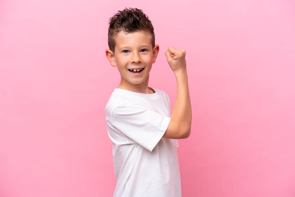 Little caucasian boy isolated on pink background doing strong gesture - Photo, Image
