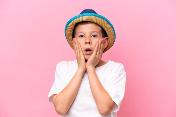 Μικρό καυκάσιο αγόρι που φοράει ένα καπέλο απομονωμένο σε ροζ φόντο - Φωτογραφία, εικόνα