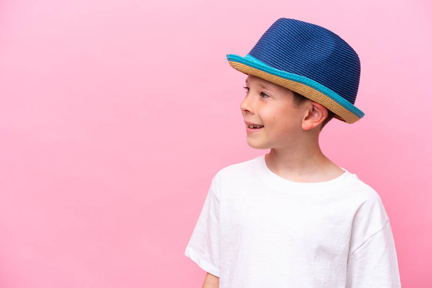 Petit garçon caucasien portant un chapeau isolé sur fond rose - Photo, image