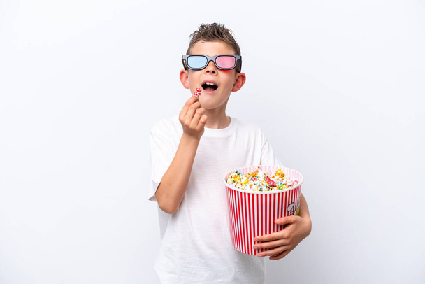 Little caucasian boy isolated on white background with 3d glasses and holding a big bucket of popcorns - Foto, Bild