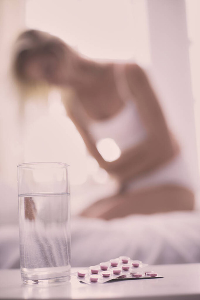 Young beautiful woman with pills lying on bed in bedroom. - Foto, Imagem