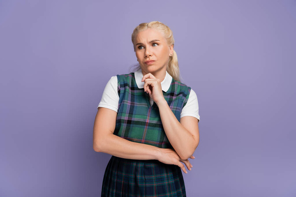 Offended student in uniform looking away isolated on purple  - Photo, image