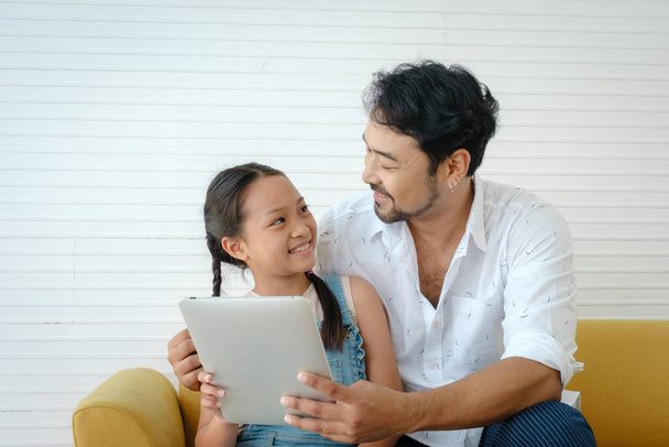 Asian father hold tablet and smile with his daughter at home. - Fotografie, Obrázek