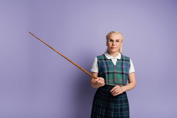 Blonde student in eyeglasses holding pointer on purple background  - Foto, Imagen