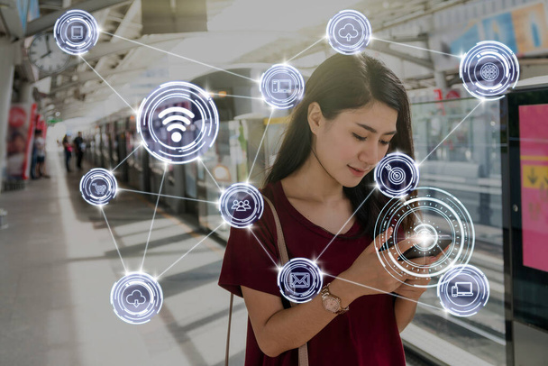 Traje de mujer asiática usando el teléfono móvil inteligente a través de la comunicación inalámbrica Conexión de la ciudad inteligente Internet de las cosas Tecnología en los carriles BTS Skytrain o metro MRT, concepto de estilo de vida
 - Foto, Imagen