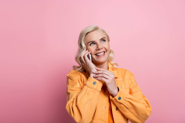 Happy blonde woman talking on mobile phone isolated on pink  - Photo, Image