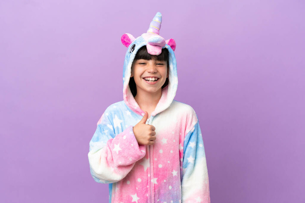 Little kid wearing a unicorn pajama isolated on purple background giving a thumbs up gesture - Fotografie, Obrázek
