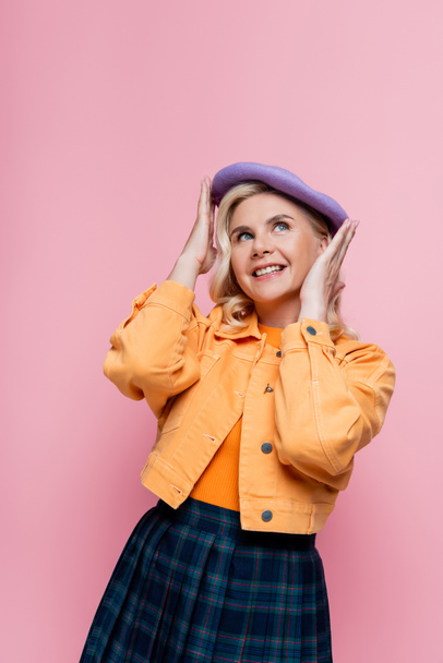 Happy woman in jacket adjusting beret isolated on pink  - Photo, image